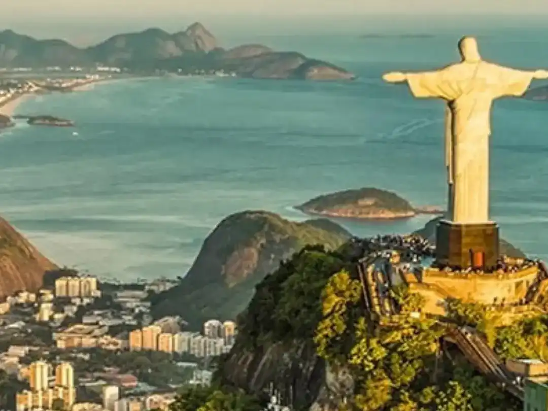 an aerial view of Rio de Janeiro, Brazil, featuring the iconic Christ the Redeemer statue on Corcovado mountain and Sugarloaf Mountain in the background.