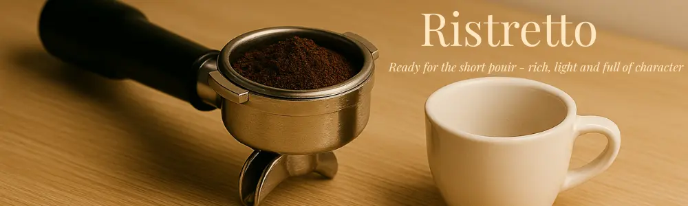 Portafilter filled with finely ground coffee beside a small white espresso cup on a wooden countertop — a minimalist setup for pulling a ristretto shot.