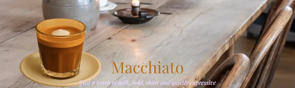 macchiato with a dollop of milk foam on top, sitting on a beige saucer on a wooden table and chairs